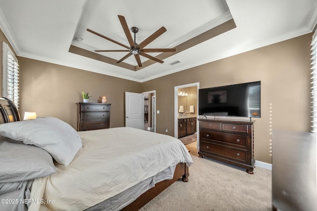 bedroom with light carpet, ceiling fan, a tray ceiling, ensuite bath, and crown molding