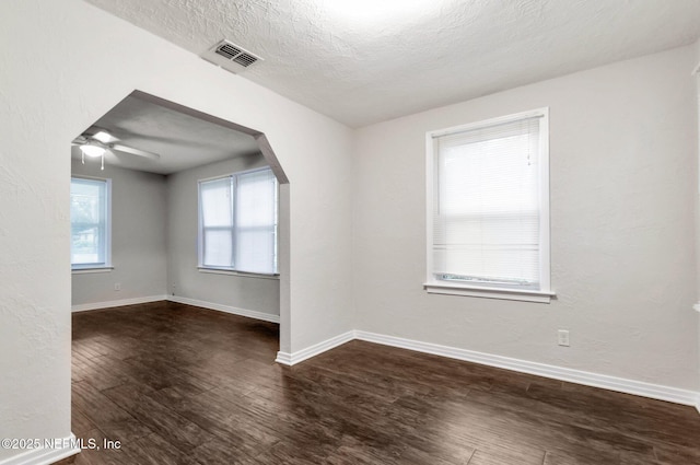 unfurnished room with ceiling fan, dark wood-type flooring, and a textured ceiling