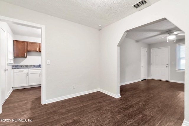 spare room with ceiling fan, dark hardwood / wood-style floors, and a textured ceiling