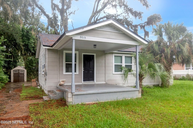 bungalow-style house with a front yard, a porch, and a shed