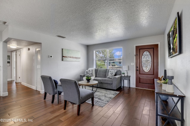 living room featuring dark hardwood / wood-style flooring and a textured ceiling