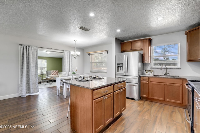 kitchen featuring decorative light fixtures, sink, hardwood / wood-style flooring, a center island, and stainless steel appliances