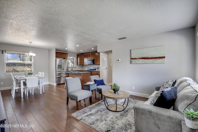 living room featuring dark wood-type flooring, a notable chandelier, and a textured ceiling