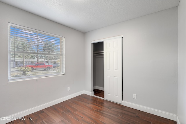 unfurnished bedroom featuring a closet, dark hardwood / wood-style flooring, and a textured ceiling