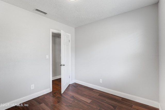 empty room with dark hardwood / wood-style floors and a textured ceiling