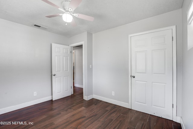 unfurnished bedroom featuring ceiling fan, dark hardwood / wood-style floors, and a textured ceiling