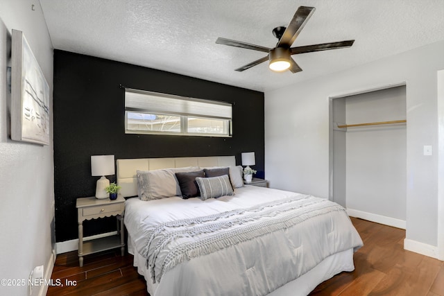 bedroom with ceiling fan, dark hardwood / wood-style floors, a textured ceiling, and a closet