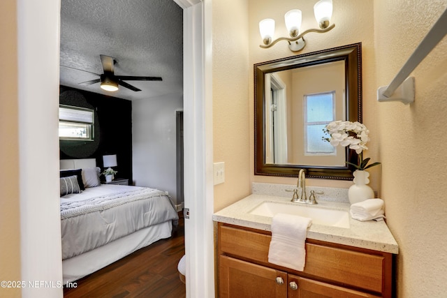 bathroom featuring wood-type flooring, vanity, ceiling fan, plenty of natural light, and a textured ceiling