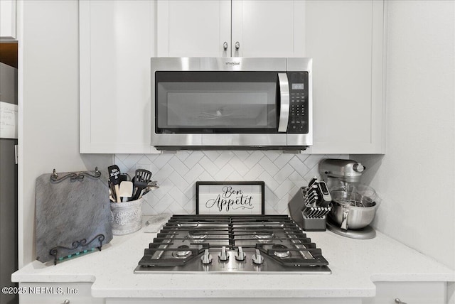 details featuring light stone counters, decorative backsplash, white cabinets, and appliances with stainless steel finishes