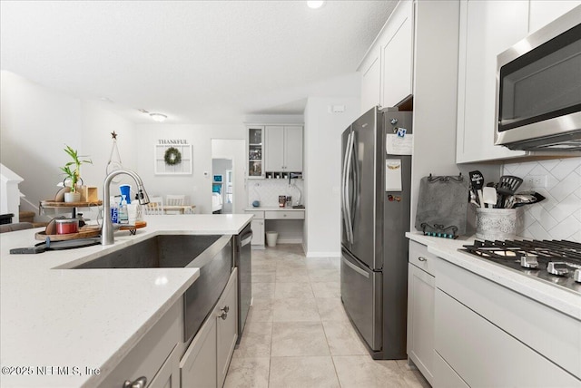 kitchen featuring sink, light tile patterned floors, white cabinets, stainless steel appliances, and backsplash