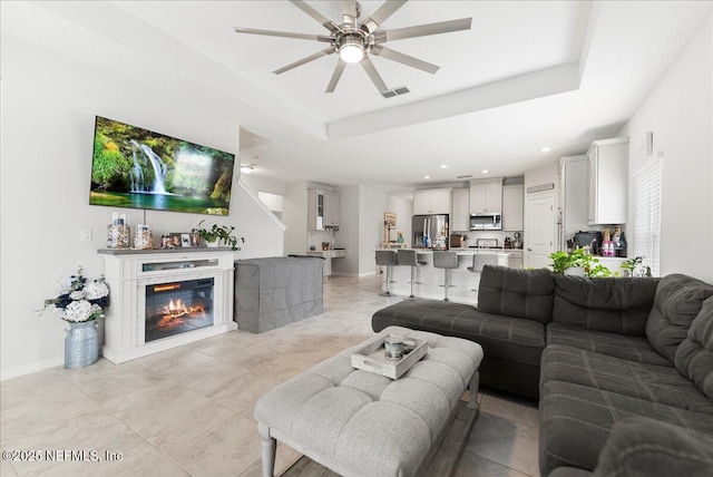 living room with a raised ceiling and ceiling fan