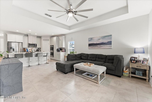 living room featuring a raised ceiling and ceiling fan