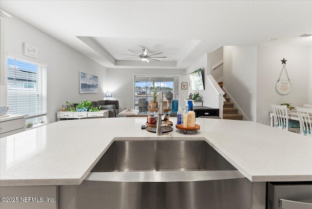 kitchen featuring plenty of natural light, a tray ceiling, and a kitchen island with sink