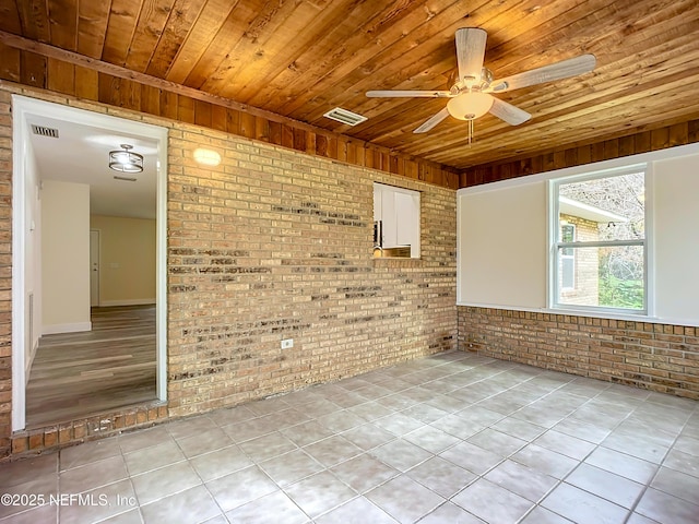 spare room with ceiling fan, wood ceiling, and brick wall