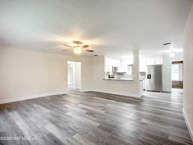 unfurnished living room featuring ceiling fan, wood-type flooring, and a textured ceiling