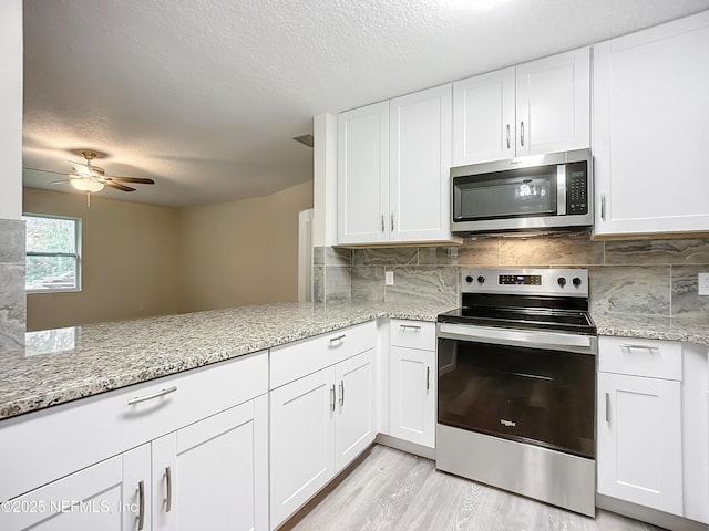 kitchen with kitchen peninsula, white cabinetry, and stainless steel appliances