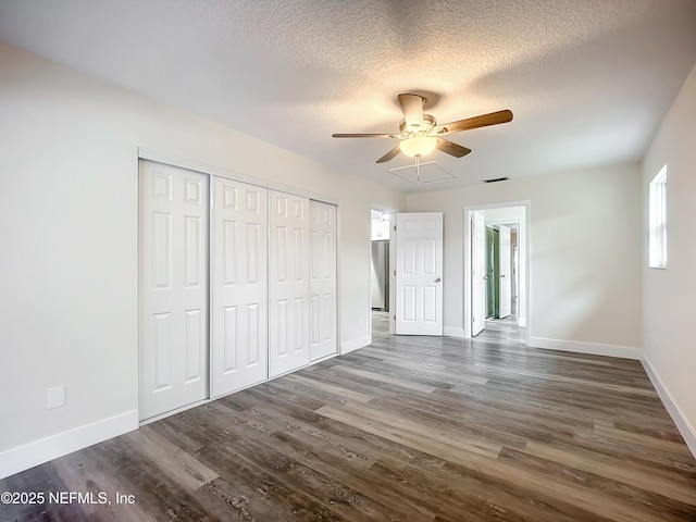 unfurnished bedroom featuring ceiling fan, a closet, dark hardwood / wood-style floors, and a textured ceiling