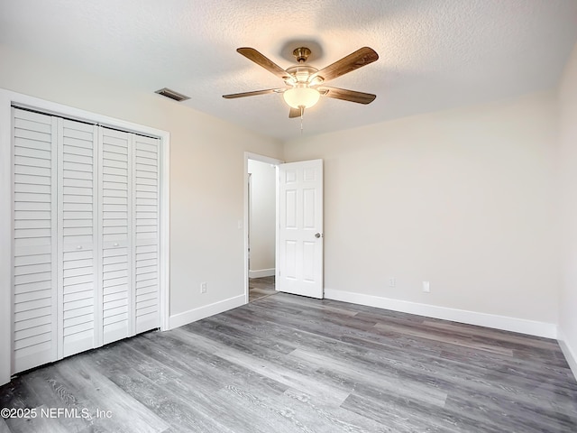 unfurnished bedroom featuring ceiling fan, hardwood / wood-style floors, a closet, and a textured ceiling