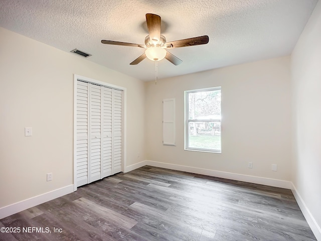 unfurnished bedroom with a textured ceiling, ceiling fan, a closet, and hardwood / wood-style floors