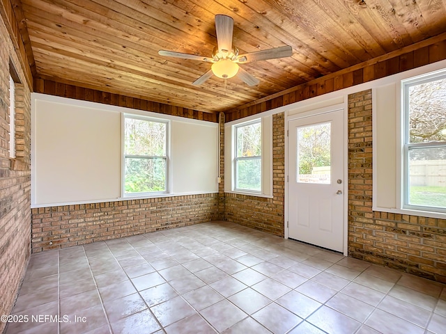 unfurnished sunroom with ceiling fan, plenty of natural light, and wood ceiling