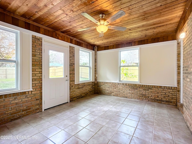 tiled spare room with ceiling fan, wooden ceiling, and brick wall