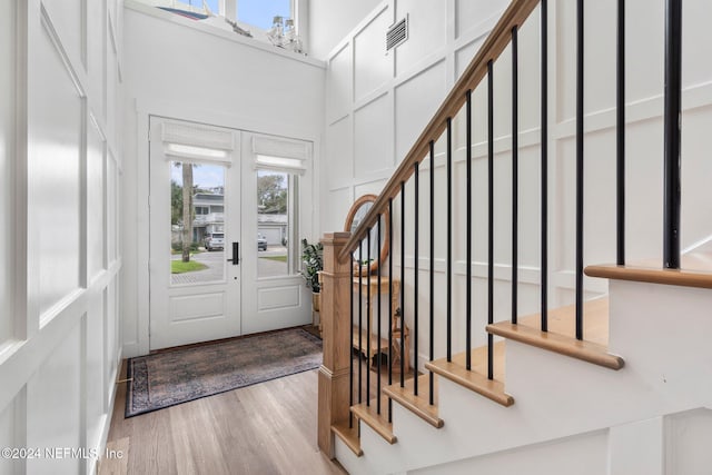 foyer entrance with light wood-type flooring and a towering ceiling