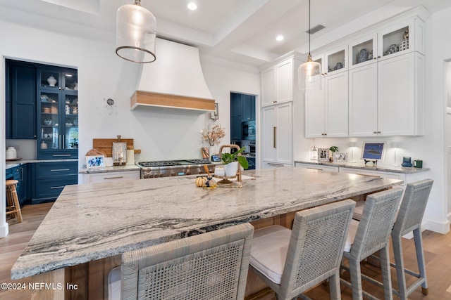 kitchen with white cabinetry, custom exhaust hood, blue cabinets, and a spacious island