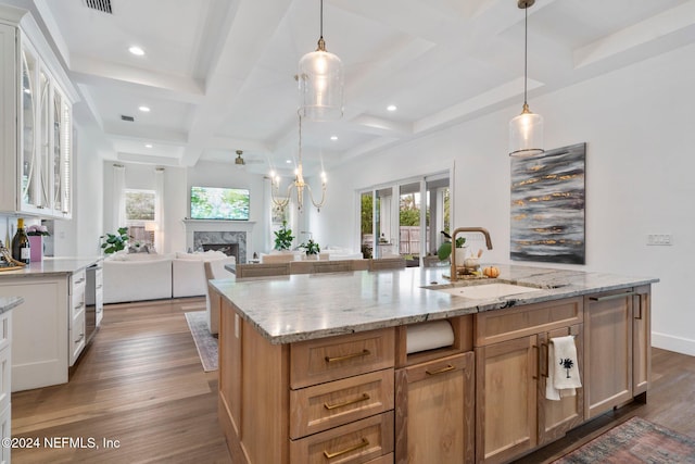 kitchen with white cabinetry, coffered ceiling, a spacious island, and sink