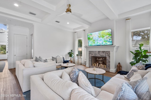 living room with a wealth of natural light, a fireplace, wood-type flooring, and beamed ceiling