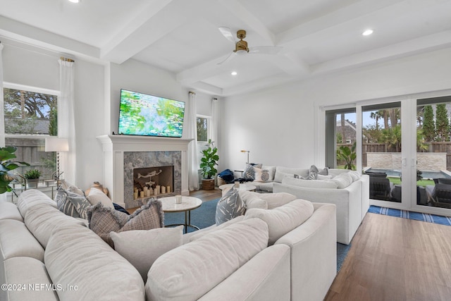 living room with beam ceiling, wood-type flooring, a fireplace, and ceiling fan