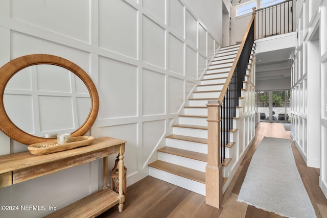 staircase with wood-type flooring and a high ceiling