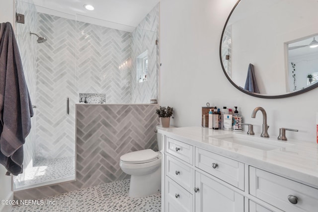 bathroom featuring toilet, vanity, tile patterned flooring, and a tile shower