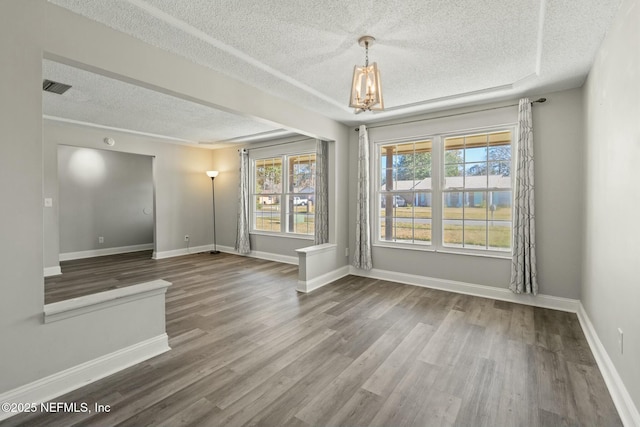 empty room featuring wood-type flooring, a textured ceiling, and an inviting chandelier