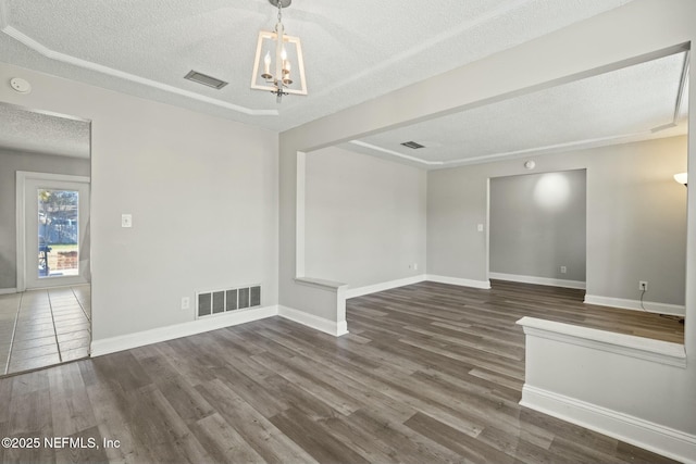 unfurnished room with a textured ceiling, dark wood-type flooring, and a notable chandelier