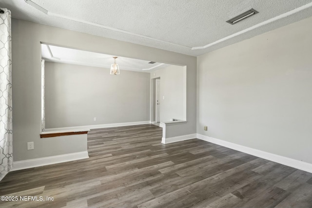 empty room with a textured ceiling and dark hardwood / wood-style flooring