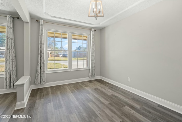 spare room with a textured ceiling, dark wood-type flooring, and a chandelier