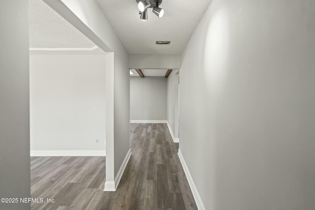 corridor featuring a textured ceiling and wood-type flooring