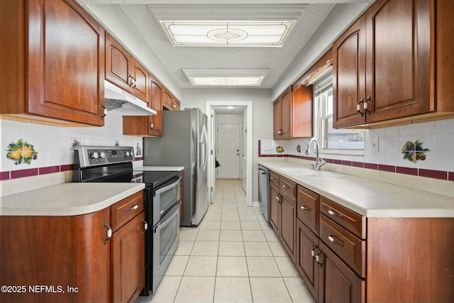 kitchen featuring tasteful backsplash, light tile patterned floors, appliances with stainless steel finishes, and sink