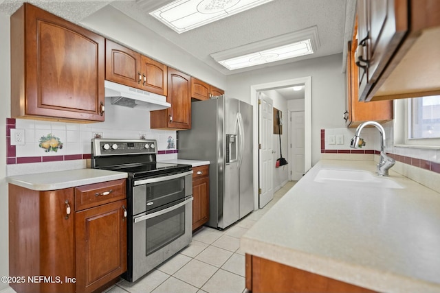 kitchen with decorative backsplash, sink, stainless steel appliances, and light tile patterned flooring