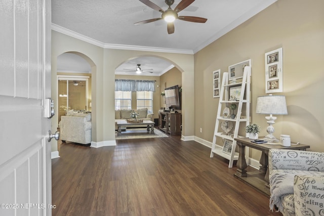 interior space with dark wood-type flooring, ceiling fan, ornamental molding, and a textured ceiling