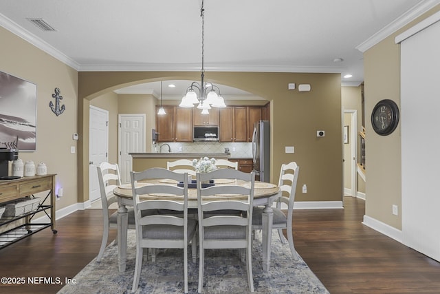 dining room with dark hardwood / wood-style flooring, crown molding, and a chandelier