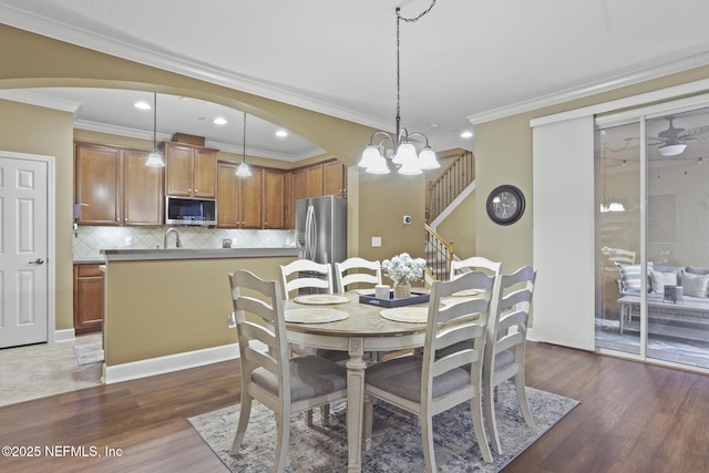 dining space with crown molding, sink, a notable chandelier, and dark hardwood / wood-style flooring