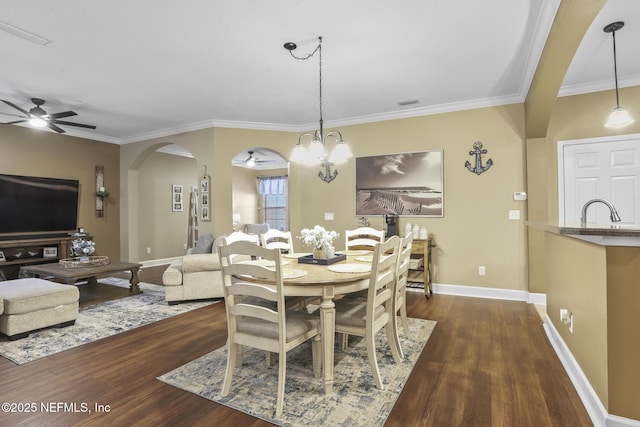 dining room featuring dark hardwood / wood-style flooring, sink, ceiling fan with notable chandelier, and crown molding