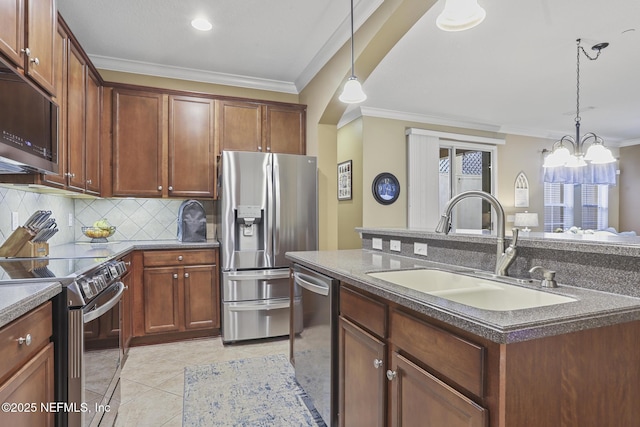 kitchen with a kitchen island with sink, sink, stainless steel appliances, and hanging light fixtures