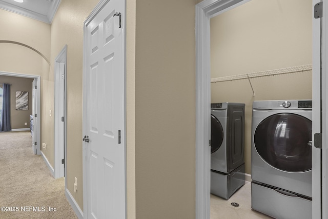 laundry area featuring crown molding, light colored carpet, and washing machine and clothes dryer