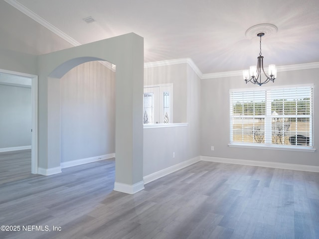 spare room with an inviting chandelier, ornamental molding, and hardwood / wood-style floors