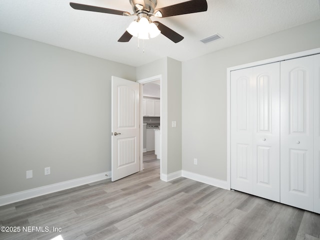 unfurnished bedroom featuring ceiling fan, light hardwood / wood-style floors, a textured ceiling, and a closet