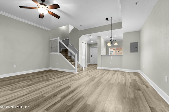 unfurnished living room featuring ceiling fan with notable chandelier, electric panel, ornamental molding, and light wood-type flooring