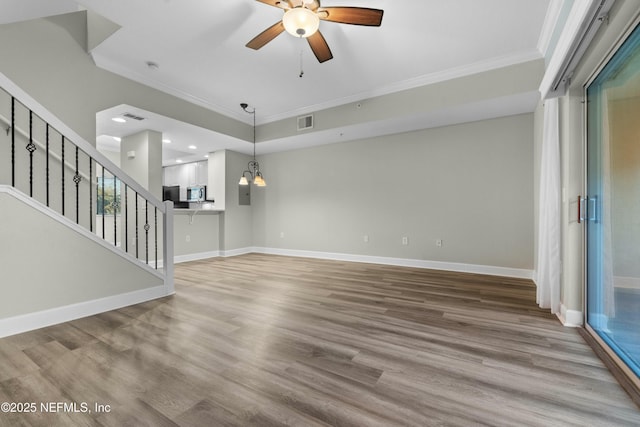 unfurnished living room featuring light wood-type flooring, ceiling fan with notable chandelier, and crown molding