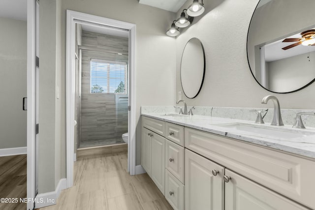 bathroom featuring toilet, ceiling fan, an enclosed shower, and vanity